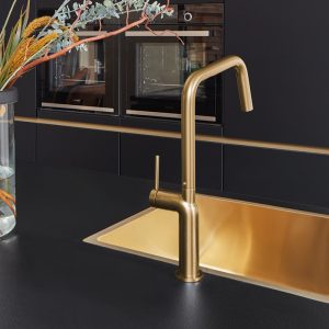 Goldene Küchenarmatur und Spüle mit schwarzer Arbeitsplatte