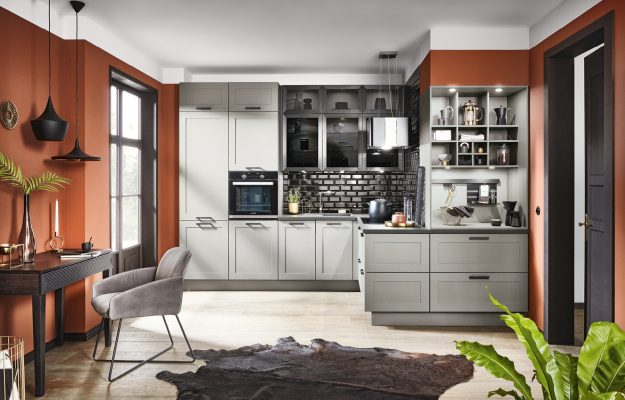 Moderne Küche mit grauen Fronten, schwarzer Fliesenrückwand und warmen Terrakotta-Wänden – stilvolle Wohnküche.