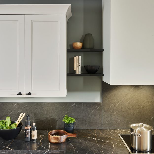 Moderne Küchenarbeitsfläche aus dunklem Stein mit weißen Fronten und frischen Zutaten