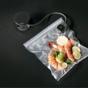 Vakuumiergerät mit frischen Garnelen, Limetten und Kräutern in Sous-vide-Beutel – moderne Küchentechnologie