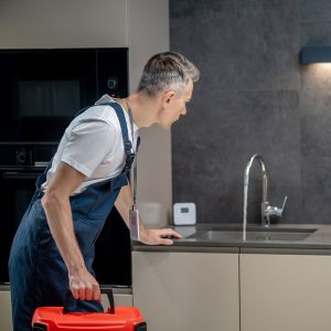 Handwerker überprüft Wasseranschluss in moderner Küche